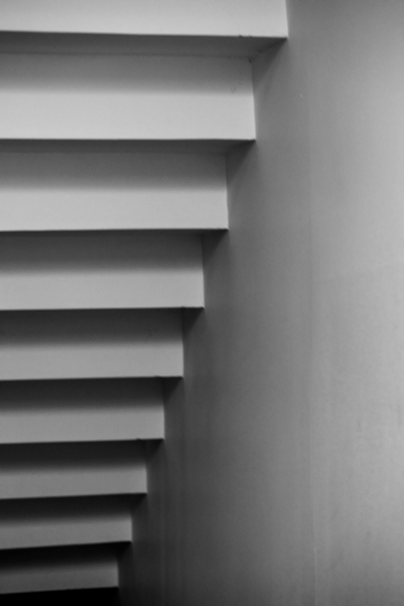 Black and white fine art photography print of minimalist cantilevered staircase steps casting geometric shadows, by Israeli artist Tamar Green