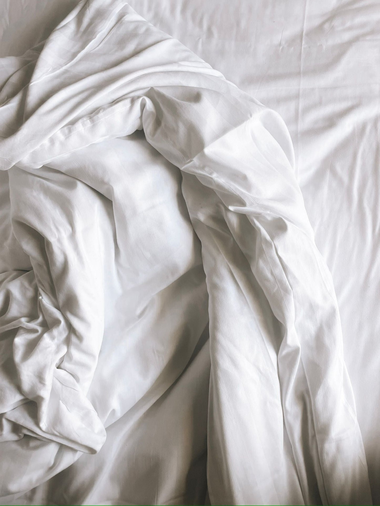 Fine art photography print of softly rumpled white bed sheets forming sculptural folds in an intimate composition, by Israeli artist Tamar Green