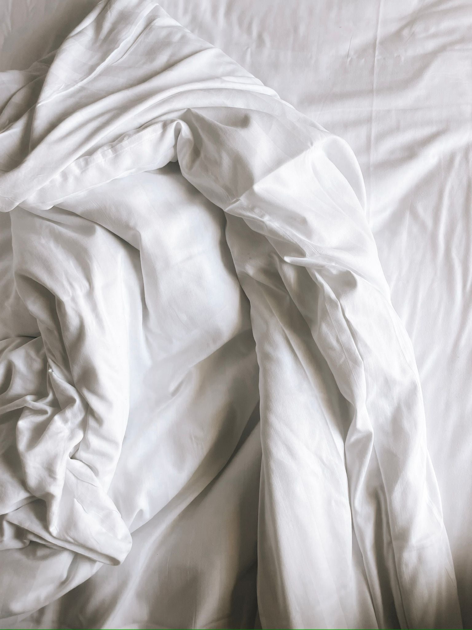 Fine art photography print of softly rumpled white bed sheets forming sculptural folds in an intimate composition, by Israeli artist Tamar Green